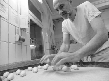 <span style='font-size:0.75em'><strong>Arbeit mit Teig</strong> Der Bäcker bereitet ein Blech mit Teigrollen für spätere Mandelstangen vor. ©Ernst Wilhelm Grüter</span>