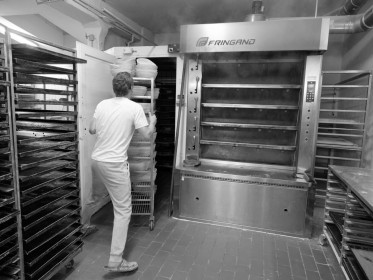 <span style='font-size:0.75em'><strong>Arbeit mit Teig</strong> Der Bäcker bringt gerade einen Bäckereiwagen mit Brotteiglingen in den Gärraum. ©Ernst Wilhelm Grüter</span>