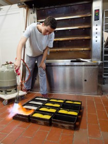 <span style='font-size:0.75em'><strong>Arbeiten am Ofen</strong> Die Bäckerin flämmt ein Kastenbrot. Neben einer besonderen Optik verändert sich die Kruste und es werden besondere Röstaromen erzeugt. ©Ernst Wilhelm Grüter</span>
