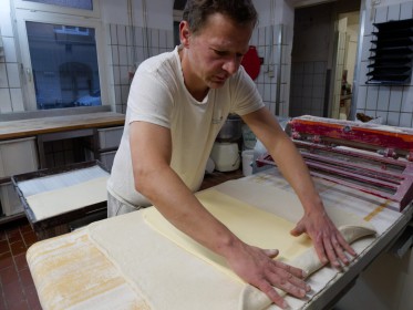 <span style='font-size:0.75em'><strong>Arbeiten mit Teig</strong> Der Bäcker bereitet die Einarbeitung einer großen Menge von Butter in den Blätterteig für Croissants ein. ©Ernst Wilhelm Grüter</span>