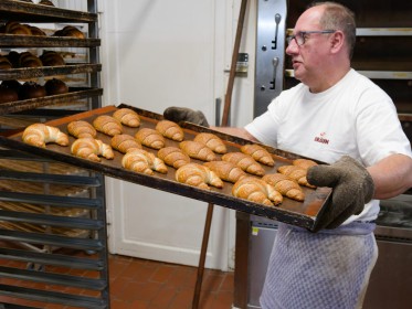 <span style='font-size:0.75em'><strong>Erweiterung</strong> Ein heißes Blech mit frischen Croissants wird in den Bäckereiwagen geschoben. ©Ernst Wilhelm Grüter</span>