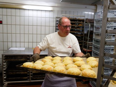 <span style='font-size:0.75em'><strong>Reportage Lindenbackt</strong> Ein heißes Blech mit Käsebrötchen wird zum Abkühlen in den Bäckereiwagen geschoben. ©Ernst Wilhelm Grüter</span>