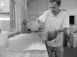 <span style='font-size:1.10em'>Das Ausbringen von Zimt auf den Teig für das Zimtgebäck.</span>