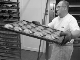 <span style='font-size:1.10em'>Der Bäcker schiebt das Bleck mit den noch heißen Coissants zum Abkühlen in den Bäckereiwagen.</span>